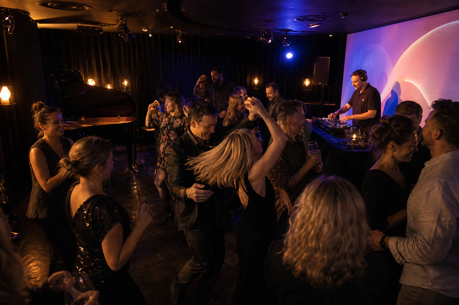 Guests dancing with a DJ beside the Downtown Piano Lab stage and concert grand piano
